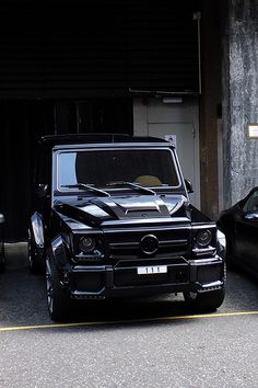 two black cars parked next to each other in front of a building with an open door