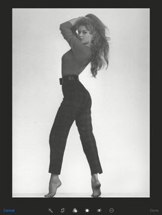 a black and white photo of a woman with her hair in the air, wearing high heels