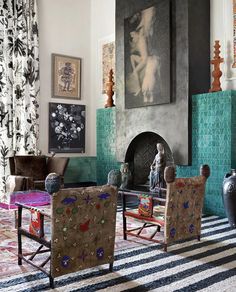 a living room filled with lots of furniture and paintings on the wall next to a fire place