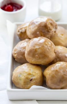 a white plate topped with donuts covered in icing next to a cup of sauce