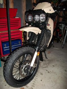 a white motorcycle parked in a garage next to some tools