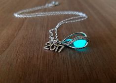 a necklace with the word 2013 written on it and a glowing blue stone in the center