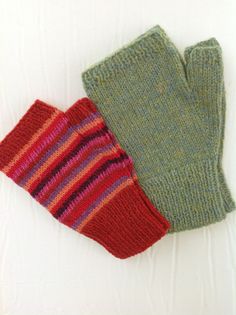 two knitted mittens sitting next to each other on top of a white surface