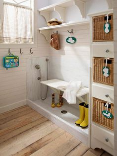 a white bathroom with yellow rubber boots on the floor and wooden wall shelves above it