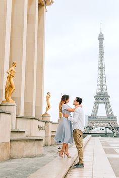 a man and woman standing next to each other near the eiffel tower in paris