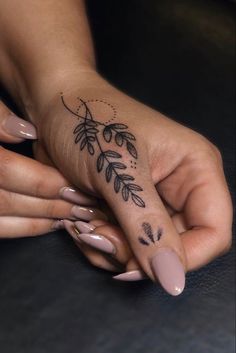 a woman's hand with a tattoo on her left thumb and fingers, holding the other