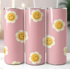 three pink tumblers with yellow and white flowers on them, one has a smiley face