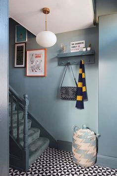 a hallway with blue walls, black and white flooring and an iron basket hanging on the wall