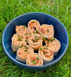 a blue bowl filled with rolls on top of green grass