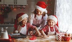 three children in santa hats are making cookies