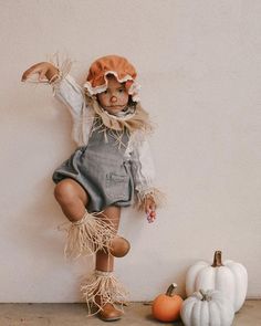 a doll is posed next to some pumpkins