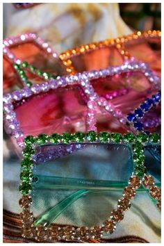 three pairs of colorful sunglasses sitting on top of a white cloth covered table next to each other