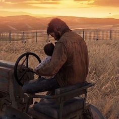 a man sitting in the driver's seat of an old farm tractor holding a baby