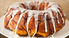 a bundt cake covered in icing on a white plate with a brown background