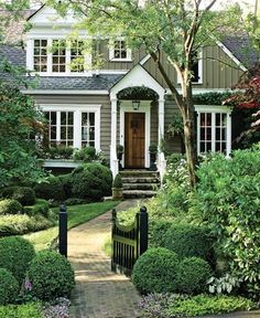 a house that has some bushes in front of it and trees on the other side