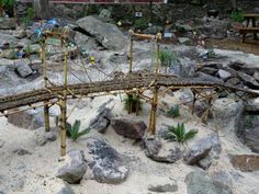 a miniature bridge made out of bamboo sticks and rocks with plants growing on the top