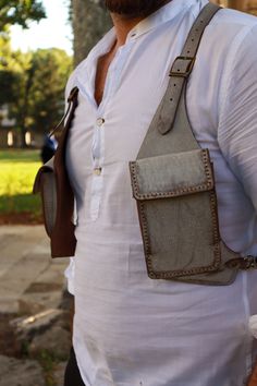 a man with a beard wearing a white shirt and brown leather suspenders