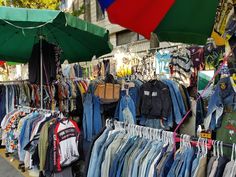 an outdoor market with clothes and umbrellas for sale