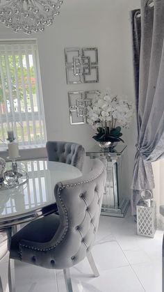 a dining room table with chairs and a chandelier hanging from the ceiling in front of a window