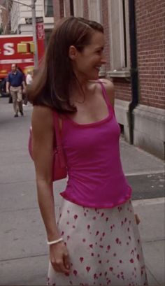 a woman is walking down the street talking on her cell phone while wearing a pink tank top