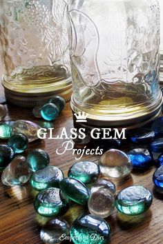 glass gems are scattered on a table next to two jars and one is filled with them