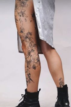 the legs and ankles of a woman with flowers on her leg, wearing black combat boots