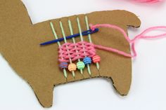 an ornament made out of yarn and knitting needles on top of a piece of cardboard