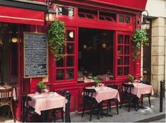 the outside of a restaurant with red walls and tables