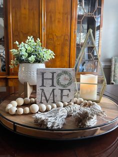 a table topped with a vase filled with flowers next to a sign that says home