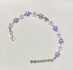 Nothing says warm weather and sun-soaked days like lightweight daisy chains and lavender! This beautiful bracelet is hand-crafted using glass seed beads and a silver zinc alloy heart charm in the middle. These gorgeous little flower chains are also adjustable in length with the extra 1 inch chain and lobster claw closure, while being strung on invisible string that stretches! This bracelet is dainty, elegant, and cute while also being so weightless it feels like you aren't even wearing a bracelet! Handmade Trendy Lavender Jewelry, Trendy Handmade Lavender Jewelry, Summer Handmade Purple Beaded Bracelets, Cute Heart Beads Jewelry For Summer, Adjustable Silver Beaded Bracelets For Spring, Casual Handmade Lavender Jewelry, Handmade Purple Bracelets For Summer, Summer Heart Beads Bracelet Jewelry, Spring Silver Beaded Bracelets As Gift