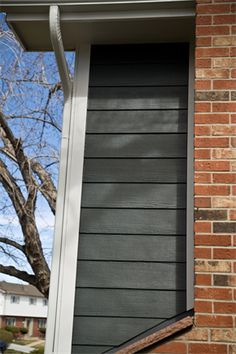 an open window on the side of a brick building with a tree in the background