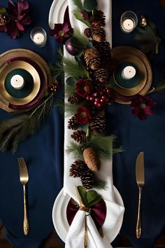 the table is set with pine cones, berries and candles