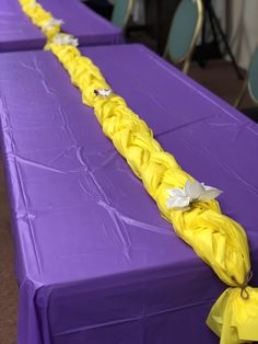 two purple tables covered in yellow cloths with white paper bows on each one end