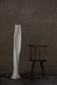 a chair next to a tall white sculpture