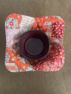 a black bowl sitting on top of an orange and pink quilt