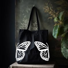 "This Butterfly Tote Bag will be your next everyday bag. Whether it's used as a grocery bag, school bag, or as a work bag; it will be the perfect bag or yourself to give as a gift.  The minimalist design will match everything but is unique enough can stand out on its own! Standard Tote Bag Classic Canvas 100% Cotton Dimensions: 15\"W x 16\"H , 21\" Handles Large Canvas Tote Bag Heavy Canvas with squared off bottom Dimensions: 20\"W x 15\"H x 5\"D , 23\" Handles Heavy Canvas Zipper Tote Bag  Heav Eco-friendly Canvas Bag For School, Eco-friendly Reusable Canvas Bag For School, Everyday Reusable Canvas Shoulder Bag, Reusable Canvas Shoulder Bag For Everyday Use, Reusable Canvas School Bag, Reusable Tote Canvas Bag For Daily Use, Reusable Canvas Bag For Everyday Use, Everyday Canvas Tote Bag For Back To School, Eco-friendly Ink Tote Bags For Everyday Use