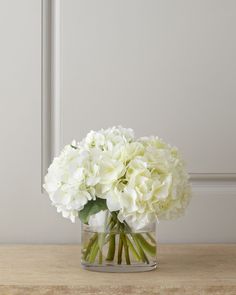 a vase filled with white flowers on top of a wooden table