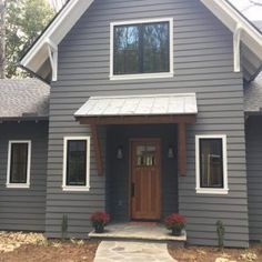 a gray house with white trim on the front door and two windows in the side