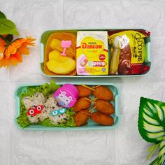 two plastic trays filled with food on top of a white table next to a plant