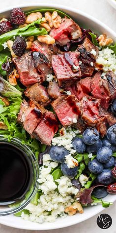 a salad with meat, blueberries and feta cheese