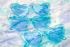 four blue heart shaped sunglasses laying on top of a white and blue background with bubbles