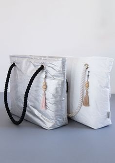 two white bags with tassels on the handles