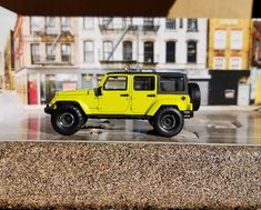 a yellow toy jeep is parked on the street in front of some buildings and cars