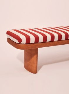 a red and white striped bench with wooden legs