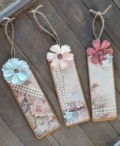 three bookmarks with flowers and pearls hanging from strings on a wooden floor next to a pair of shoes