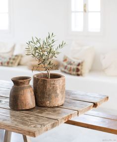 two vases sitting on top of a wooden table in front of a white couch