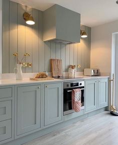 a kitchen with grey cabinets and white counter tops, gold accents on the hoods