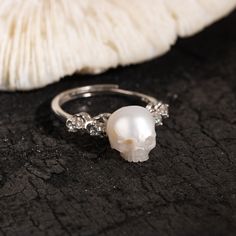 a close up of a ring with a skull on it and a mushroom in the background