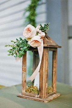 a small wooden lantern with flowers and greenery