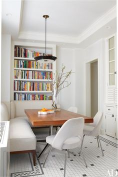 a dining room table and chairs with bookshelves in the backgroung